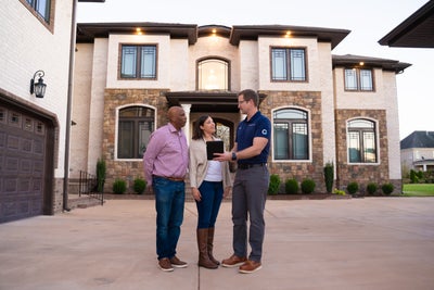 Groundworks inspector meeting with homeowners outside their house.