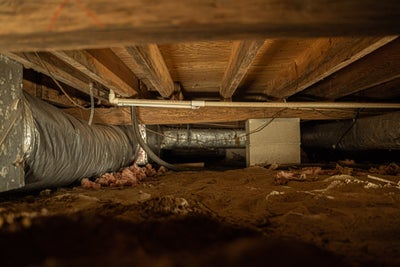 Empty crawl space with ductwork and plumbing