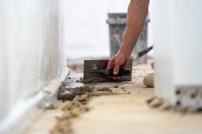 A groundworks professional installing an interior drain in a wet basement