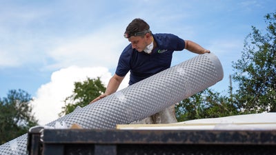 Alpha Foundations installer taking out rolled up drainage matting from a truck bed.