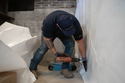 A Groundworks professional installing a vapor barrier to protect this home from excessive moisture and humidity.