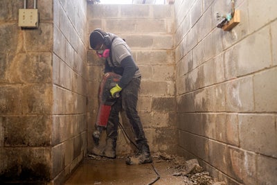 crew using a jackhammer to bust up basement concrete before installing interior drains