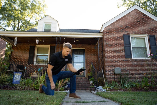 crew member kneeling over concrete sidewalk extension gap with weeds