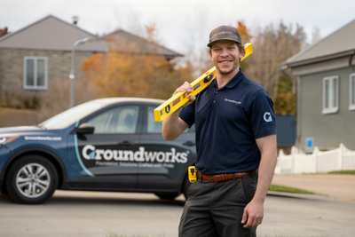 Groundworks tech smiles as he hold a level getting ready to get to work