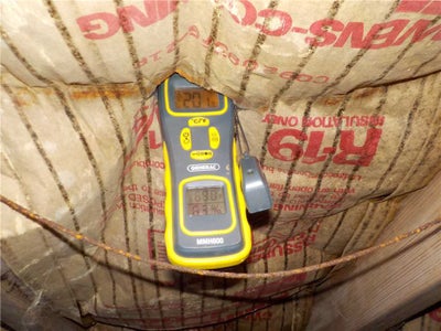 Digital hygrometer showing high humidity levels in a crawl space.