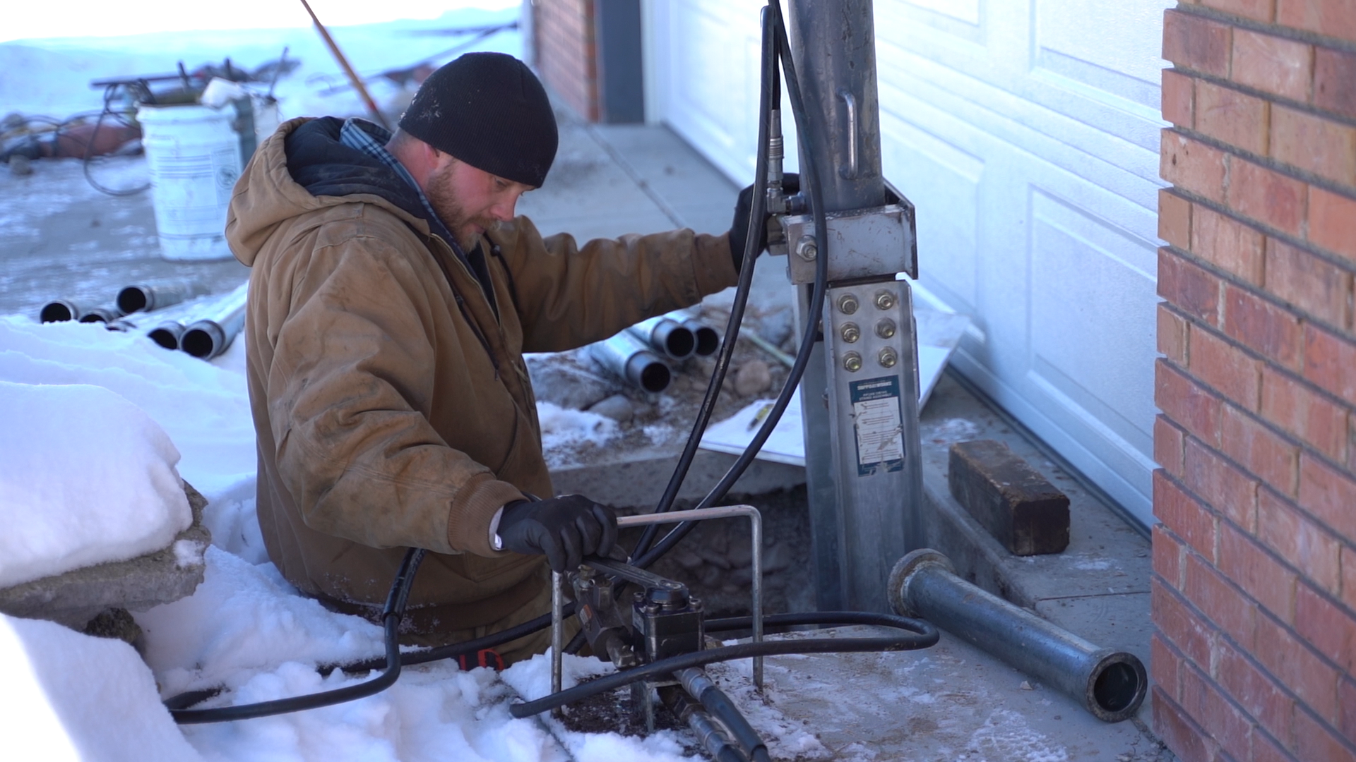 A Groundworks employee doing a foundation repair with snow and cold weather.