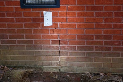 Crack at base of brick wall.