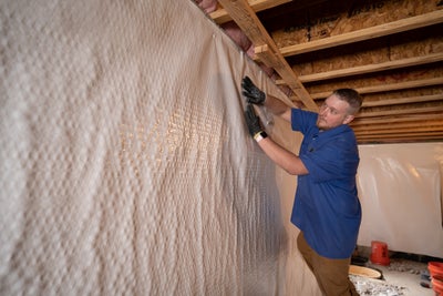 Man installing vapor barrier on a basement wall.