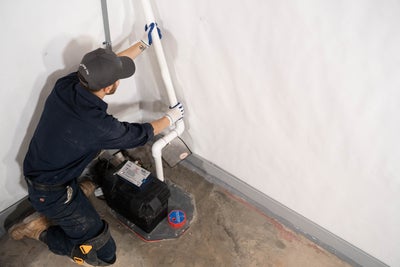 crew member installing basement waterproofing sump pump drainage