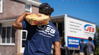JES employee carrying materials toward a truck in the background.