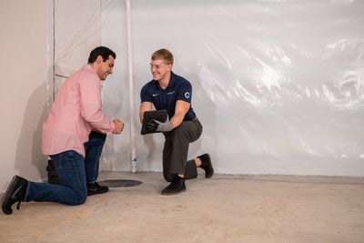 A Groundworks professional showing a homeowner how a sump pump can benefit his home.