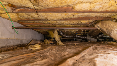 A crawl space of a home with signs of Wet Crawl Space Insulation damage
