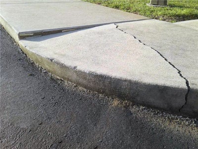 This is an uneven sidewalk that was most likely caused by soil erosion.