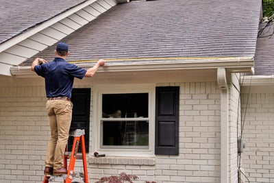 Man measuring gutters on a home.