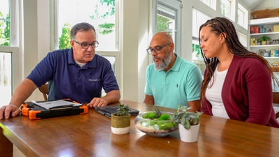Field inspector meeting with two homeowners sitting at table