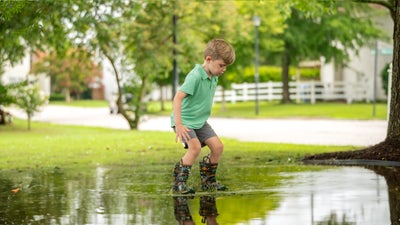 a boy standing in a puddle in the yard