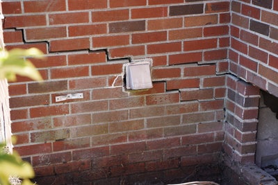 Cracks along a brick wall.