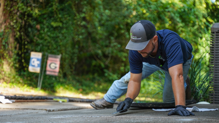 Groundworks tech repairing cracked concrete on driveway