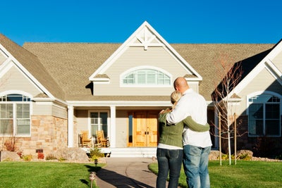 hugging couple standing in front of house