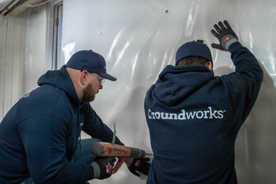 Groundworks crew attaching a vapor barrier to a basement wall