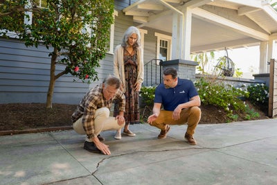 Inspector showing homeowners cracks on concrete.