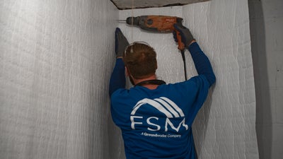 FSM employee installing vapor barrier on the wall