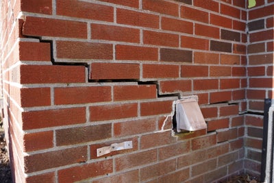 brick home with crack, displaying signs of foundation settlement