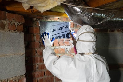 a worker installs insulation in a crawl space