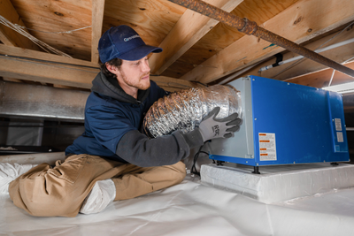 Groundworks tech installing a dehumidifier into crawl space of a home