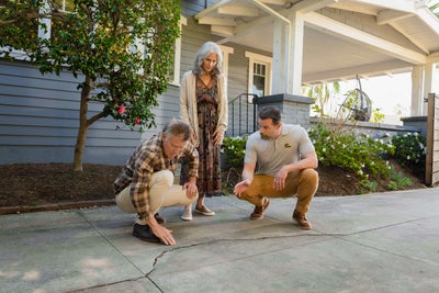 Inspector showing homeowners cracked concrete.