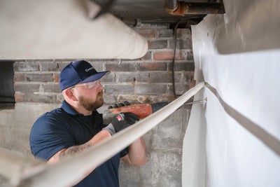 A Groundworks employee installing a vapor barrier on the wall