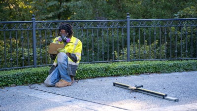crew member with clipboard evaluating concrete damage near iron fence