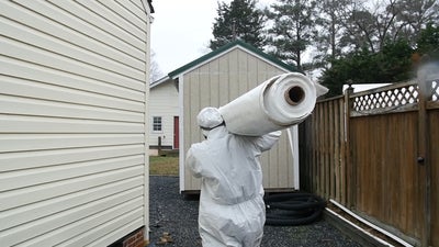 crew member carrying a rolled up vapor barrier