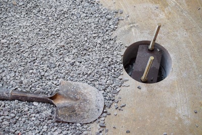 Close up of a shovel and gravel next to a slab pier.