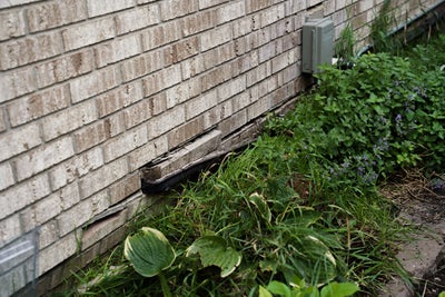 Cracked, uneven bricks on base of home.