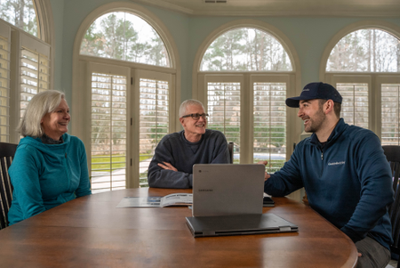 A Groundworks worker consulting repair options with an elderly couple.