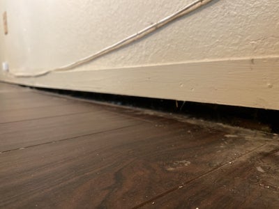 gap between the floor and a wall, indicating sagging floors