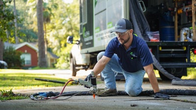 Alpha Foundations crewmember injecting polyurethane below a driveway.