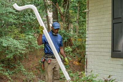 installer carrying a section of a downspout