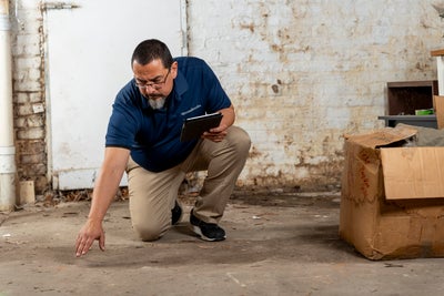 A Groundworks professional inspecting a damp basement to determine the problem areas, and the best solution.
