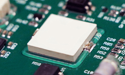 인쇄 회로 기판(PCB) 조립품의 부품 가장자리 접착 및 보강에 사용되는 Dymax 9310 광경화성 접착제의 근접 사진.