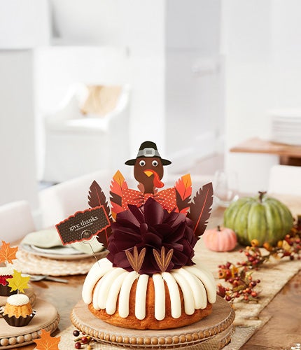 Decorated Bundt Cake with decorative Turkey with bow and paper feathers to write on