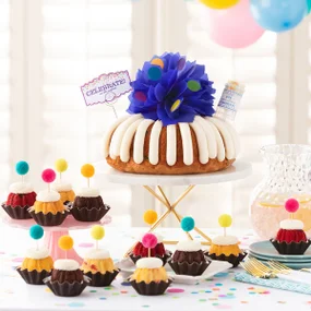 Big Bundt Cake with blue bow on top and assorted Bundtinis with celebration toppers.
