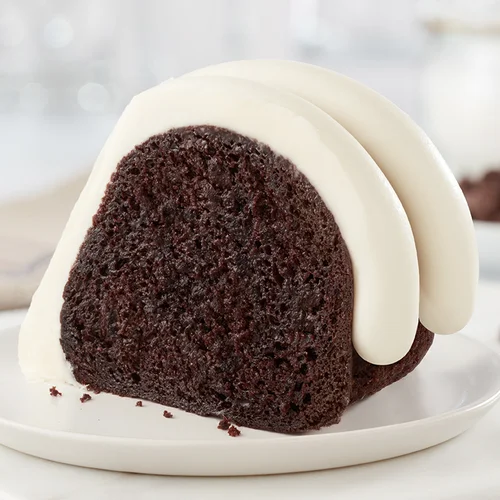 Chocolate Chocolate Chip Cake slice on a plate, with signature frosting - Shop Bundt Cakes