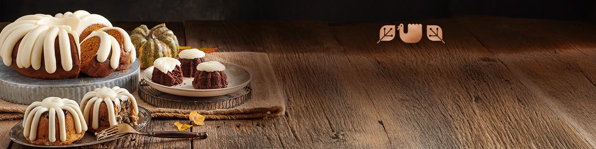 A bundt cake and assorted bundtlets and bundtinis on a wooden table.