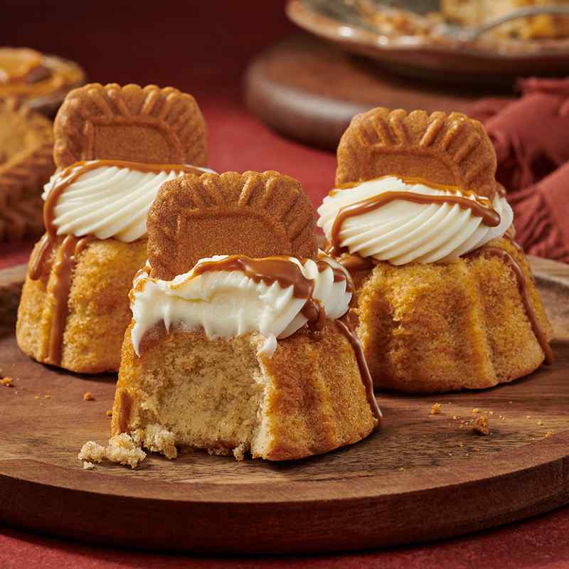 Biscoff flavor of mini Bundt cakes crowned with cream cheese sitting on a plate - Shop Bundtinis