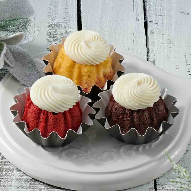 Assorted flavors of mini Bundt cakes crowned with cream cheese sitting on a plate - Shop Bundtinis