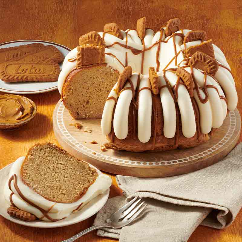 Biscoff Bundt Cake with slice out of it on a cake stand, with signature frosting - Shop Bundt Cakes