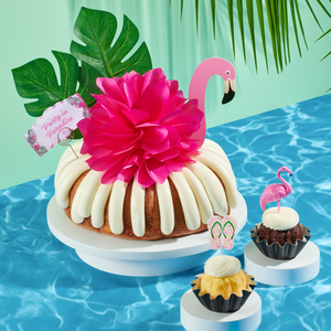 Party in Paradise Bundt Cake topped with a hot pink bow on top and a mini pinata and stick. -- Shop Now