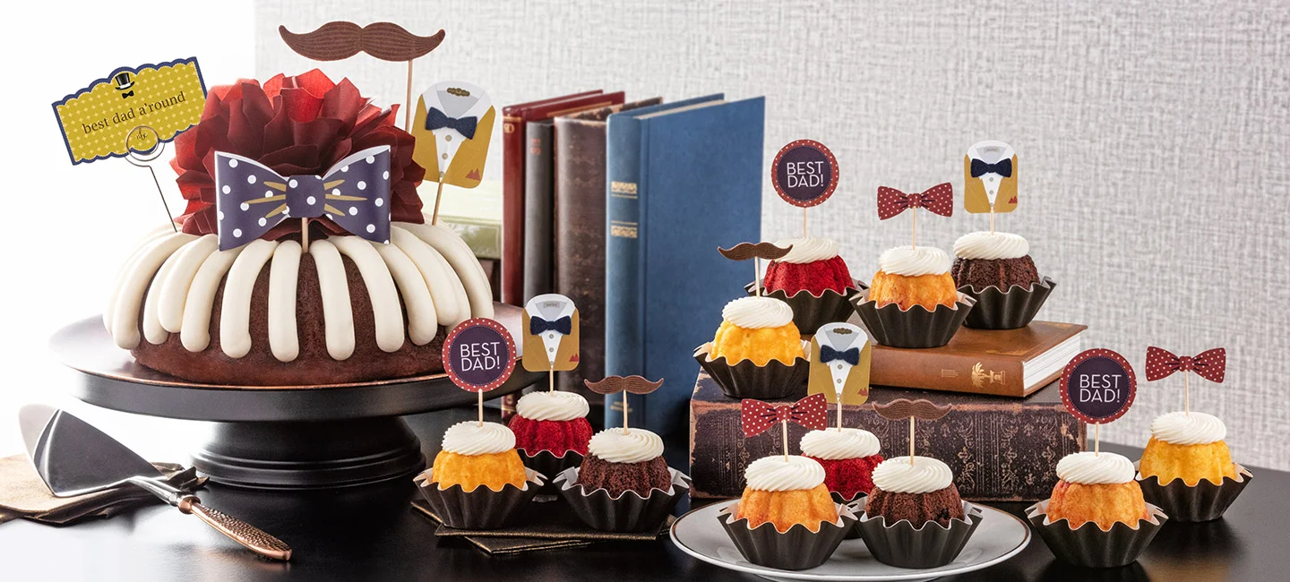 Bundt cake topped with bow and best dad a'round decorations displayed alongside Bundtinis with BEST DAD! decorations.